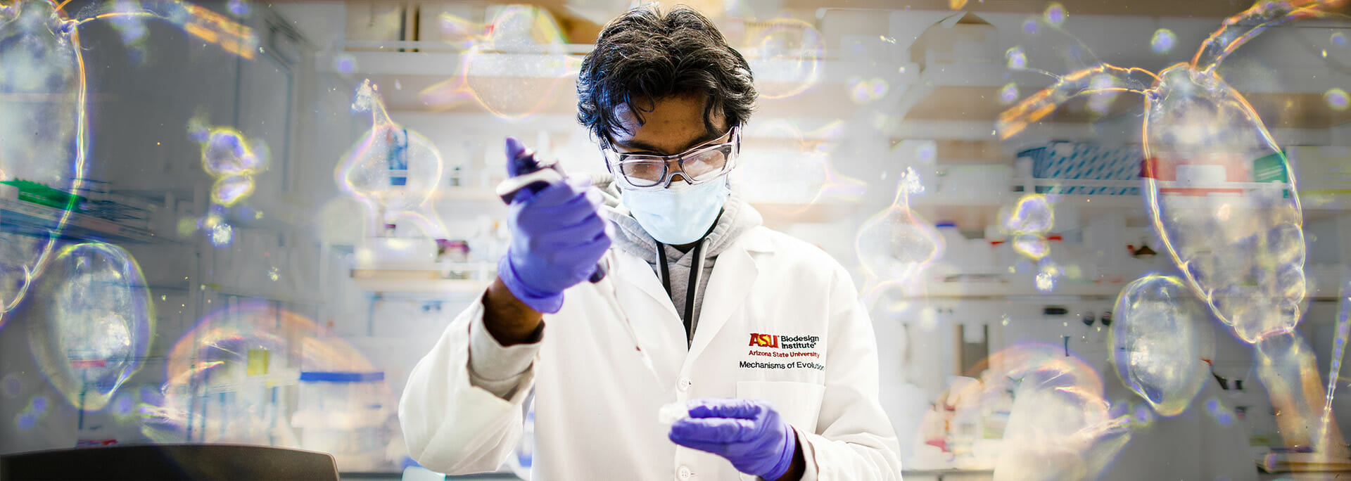 Young scientist in lab gear works with a sample at a lab table