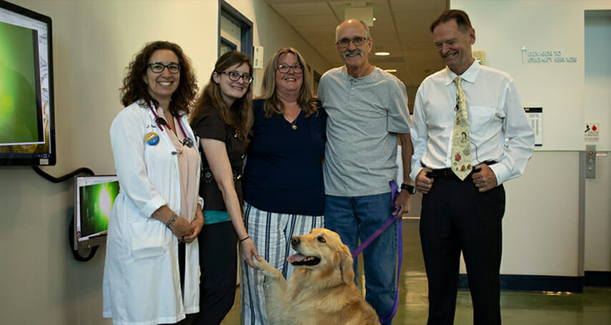 Five people in lab with golden retriever dog.